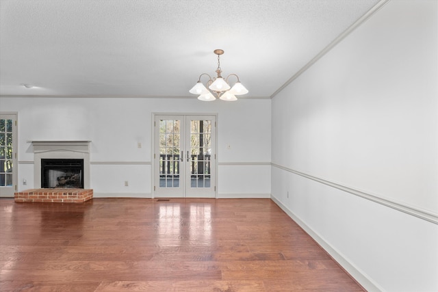 unfurnished living room featuring a textured ceiling, french doors, a fireplace, and wood finished floors