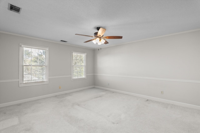 empty room with carpet floors, visible vents, and crown molding