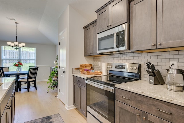 2613 Inverness Dr, Hephzibah, GA 30815 - kitchen featuring appliances with stainless steel finishes, backsplash, light wood finished floors, dark brown cabinetry, and light stone countertops
