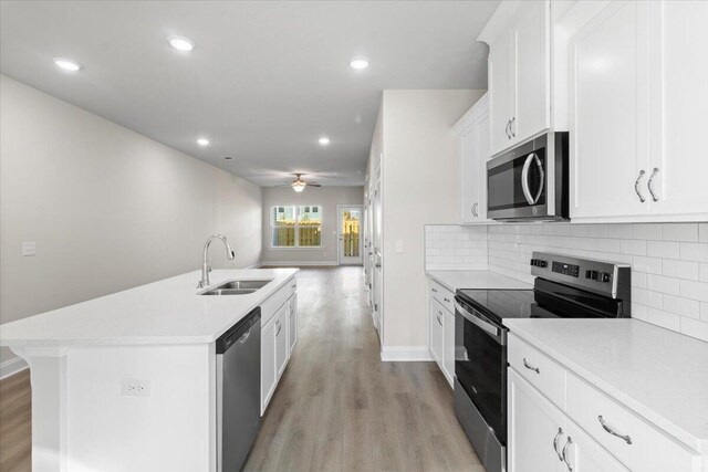 kitchen featuring appliances with stainless steel finishes, ceiling fan, sink, white cabinets, and light hardwood / wood-style floors