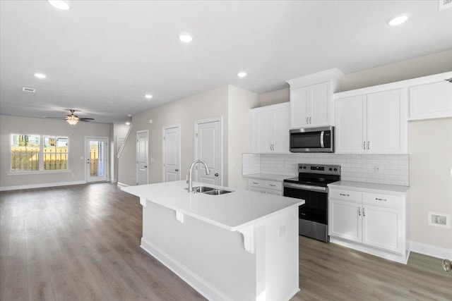 kitchen with ceiling fan, sink, stainless steel appliances, light hardwood / wood-style floors, and a kitchen island with sink