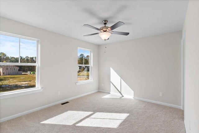 carpeted empty room featuring ceiling fan and a healthy amount of sunlight