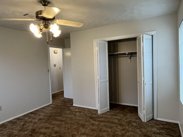 unfurnished bedroom featuring ceiling fan, a textured ceiling, and dark colored carpet