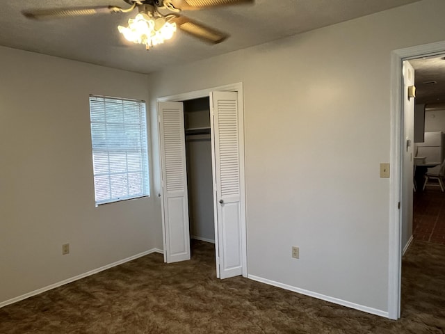 unfurnished bedroom with ceiling fan, a closet, and dark colored carpet