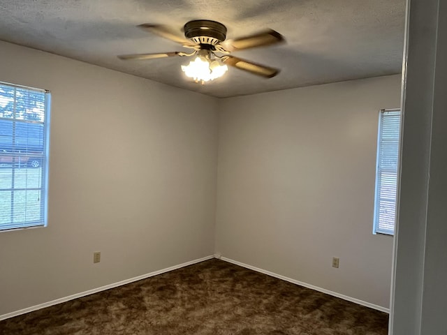 unfurnished room with ceiling fan, dark carpet, a textured ceiling, and a wealth of natural light