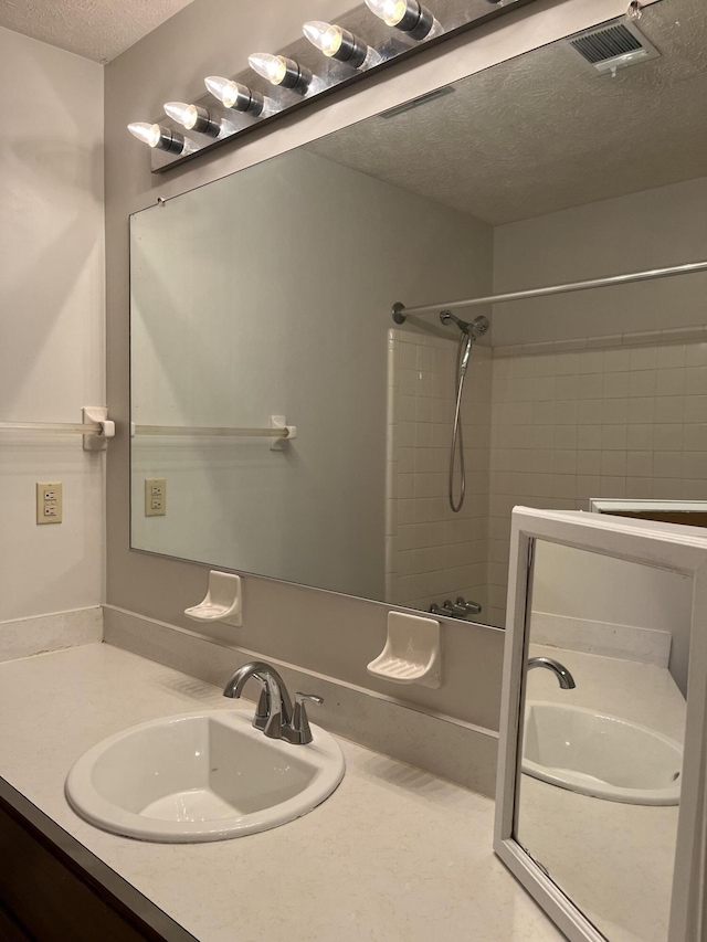 bathroom with vanity, tiled shower / bath combo, and a textured ceiling