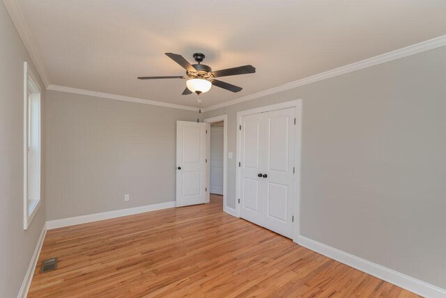 unfurnished bedroom featuring ceiling fan, a closet, light wood-type flooring, and ornamental molding