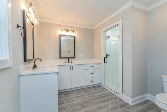 bathroom with crown molding, hardwood / wood-style floors, toilet, a shower with door, and vanity