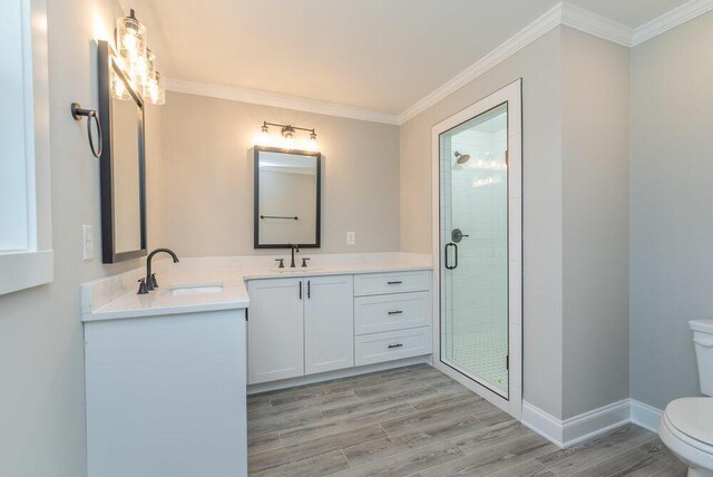 bathroom with crown molding, hardwood / wood-style floors, toilet, a shower with door, and vanity