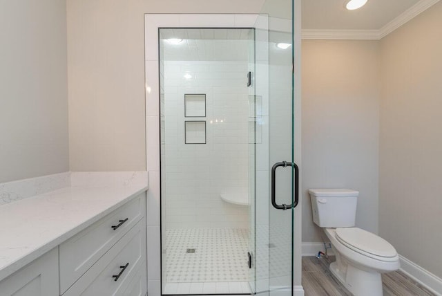 bathroom with vanity, hardwood / wood-style flooring, toilet, ornamental molding, and a shower with shower door