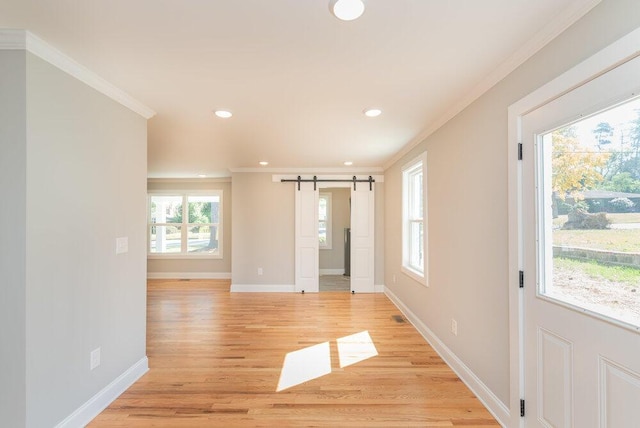 spare room with a barn door, a wealth of natural light, and crown molding