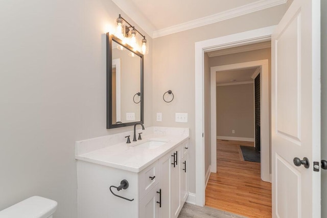 bathroom with toilet, vanity, wood-type flooring, and ornamental molding