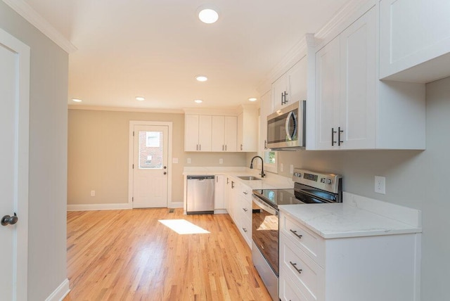 kitchen featuring light stone countertops, appliances with stainless steel finishes, sink, light hardwood / wood-style flooring, and white cabinetry