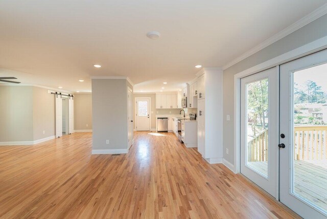 unfurnished living room with french doors, a barn door, light hardwood / wood-style flooring, and crown molding