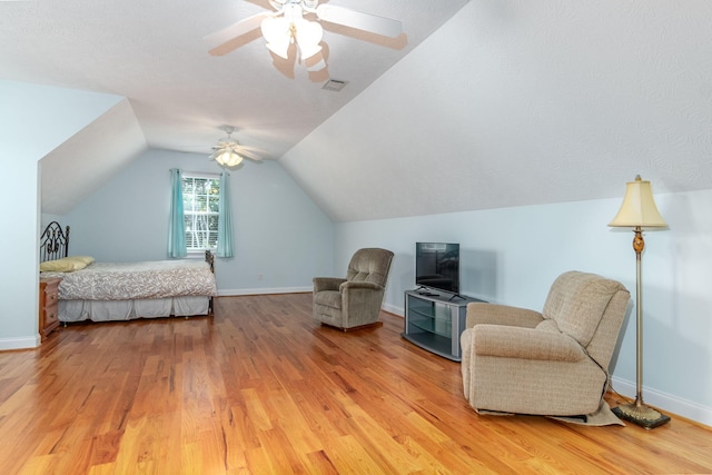 bedroom featuring ceiling fan, baseboards, lofted ceiling, light wood-type flooring, and visible vents