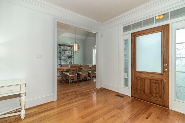 foyer with a chandelier, visible vents, ornamental molding, and light wood finished floors
