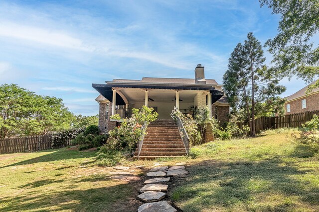 back of property featuring ceiling fan, fence, a chimney, stairs, and a yard
