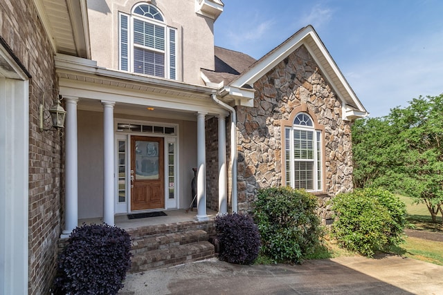 doorway to property with covered porch and stone siding