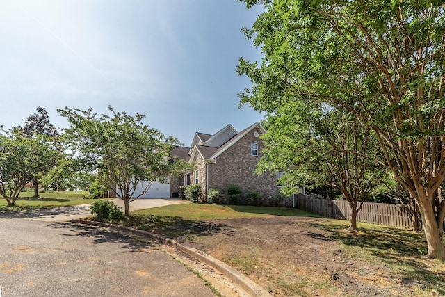 view of front of house with fence, brick siding, a garage, a front yard, and driveway