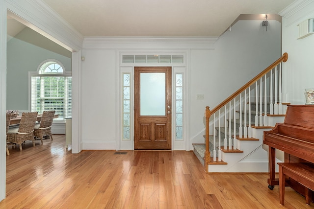 entryway with visible vents, ornamental molding, light wood finished floors, and stairs