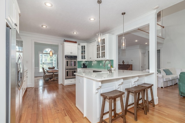 kitchen featuring crown molding, a sink, appliances with stainless steel finishes, and light wood-type flooring