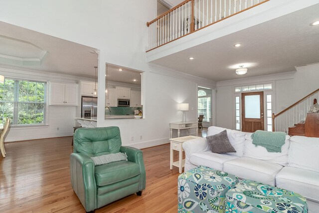 living area featuring crown molding, light wood finished floors, stairs, recessed lighting, and baseboards