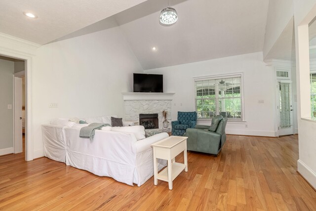 living room with light wood-style floors, vaulted ceiling, baseboards, and a fireplace