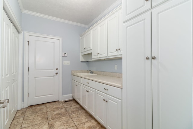 laundry room with crown molding, a sink, baseboards, and visible vents