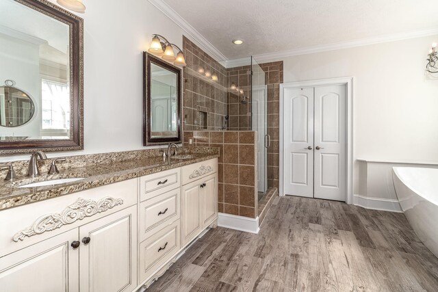 full bath featuring crown molding, a shower stall, a sink, and wood finished floors