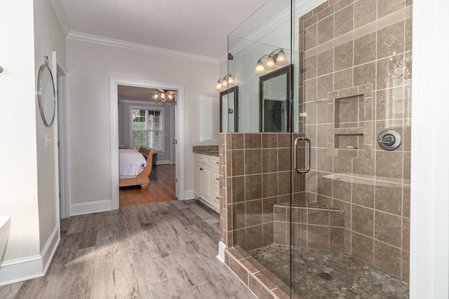 ensuite bathroom featuring crown molding, wood finished floors, baseboards, ensuite bathroom, and a stall shower