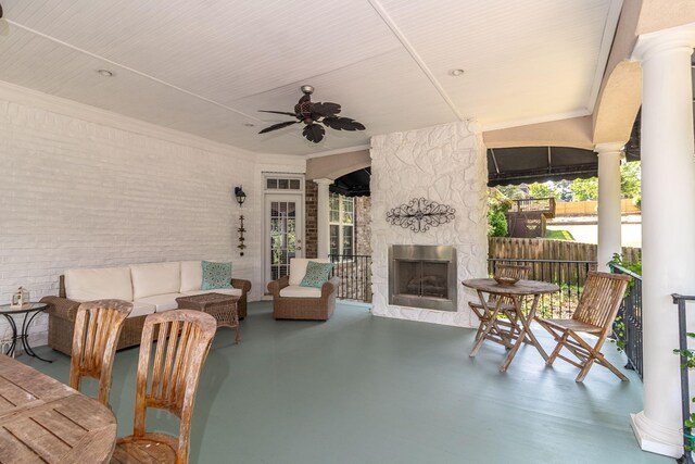 view of patio featuring fence, an outdoor living space with a fireplace, and ceiling fan