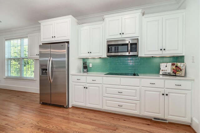 kitchen featuring crown molding, light countertops, stainless steel appliances, light wood-type flooring, and visible vents