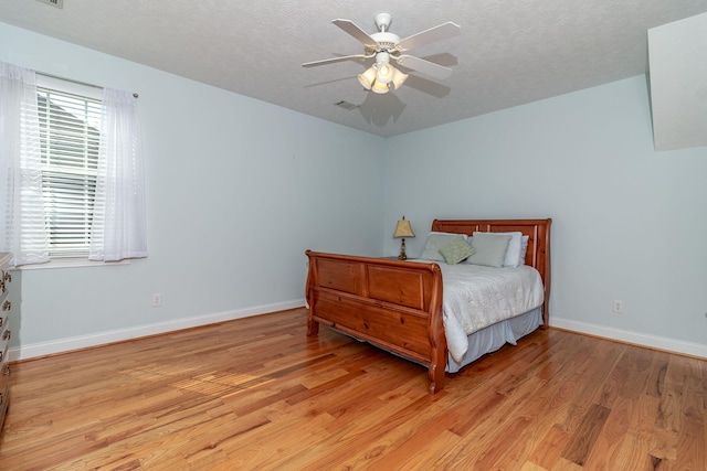 bedroom featuring a textured ceiling, visible vents, baseboards, and light wood-type flooring