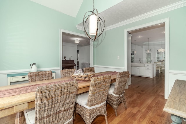 dining room featuring crown molding, wood finished floors, and vaulted ceiling