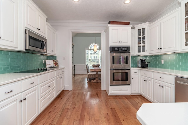 kitchen with light countertops, white cabinets, stainless steel appliances, and light wood-style flooring