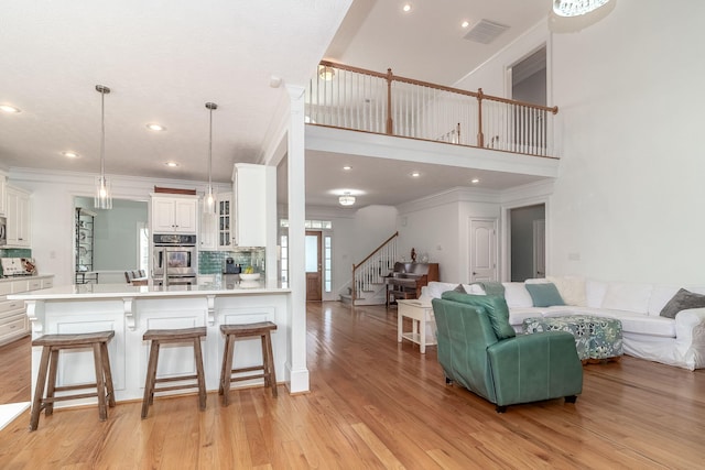 living area with light wood-style floors, ornamental molding, stairs, and visible vents