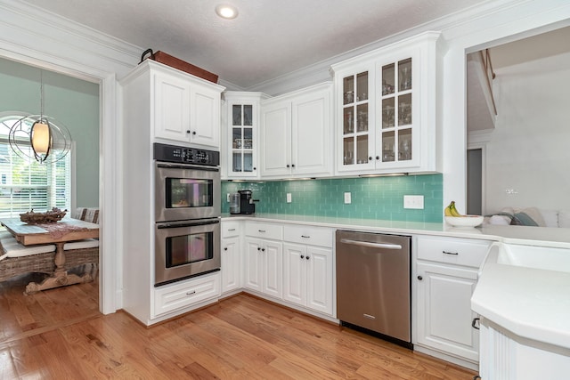 kitchen with light countertops, appliances with stainless steel finishes, backsplash, and white cabinetry