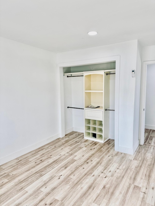 unfurnished bedroom with light hardwood / wood-style floors, a closet, and a barn door