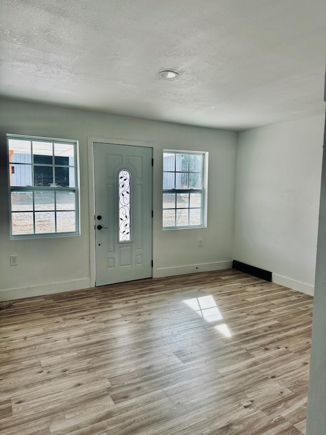 foyer entrance featuring a textured ceiling and light hardwood / wood-style floors