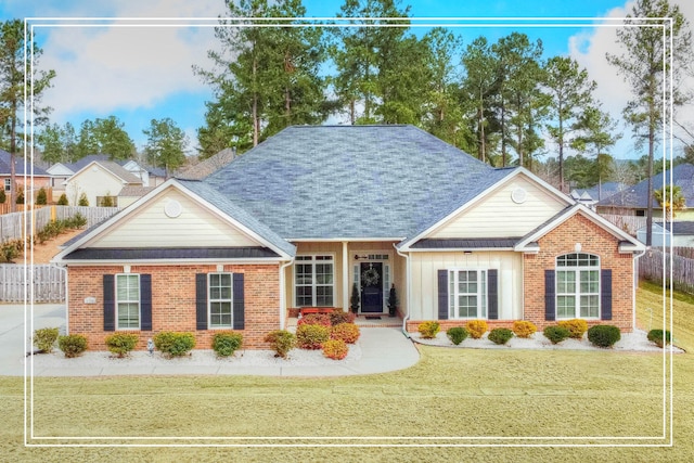 view of front of house featuring brick siding, roof with shingles, and a front lawn