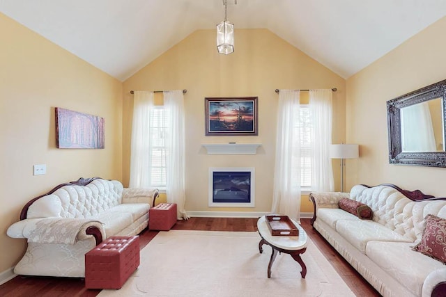 living room with baseboards, lofted ceiling, dark wood-type flooring, and a glass covered fireplace