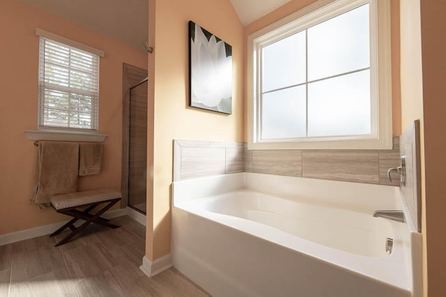 full bathroom with a wealth of natural light, a stall shower, baseboards, and a garden tub