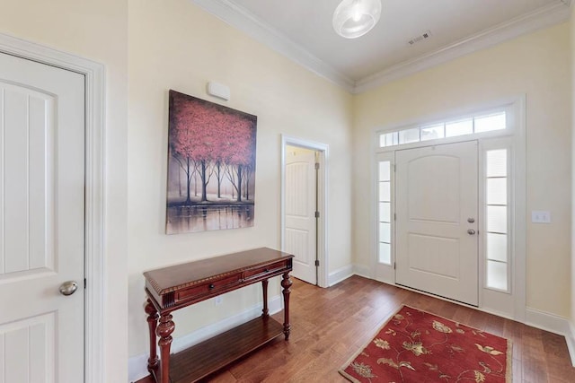 foyer entrance with visible vents, crown molding, baseboards, and wood finished floors