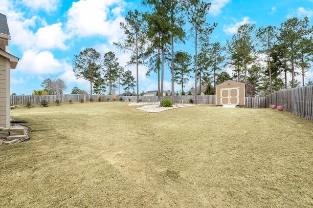 view of yard with an outbuilding, a fenced backyard, and a storage shed