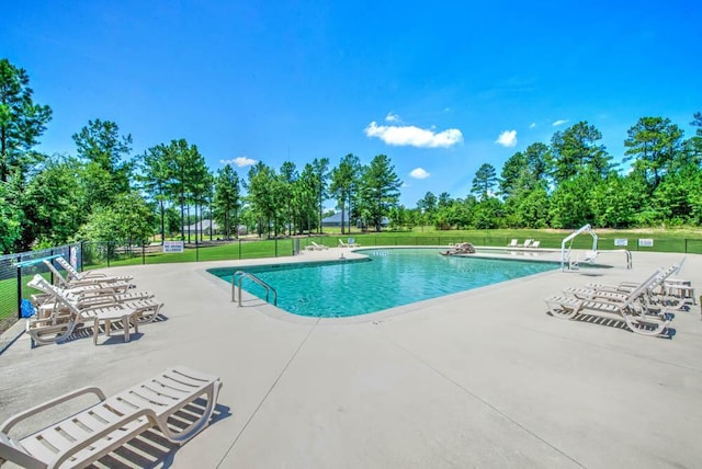 community pool featuring a patio, a yard, and fence