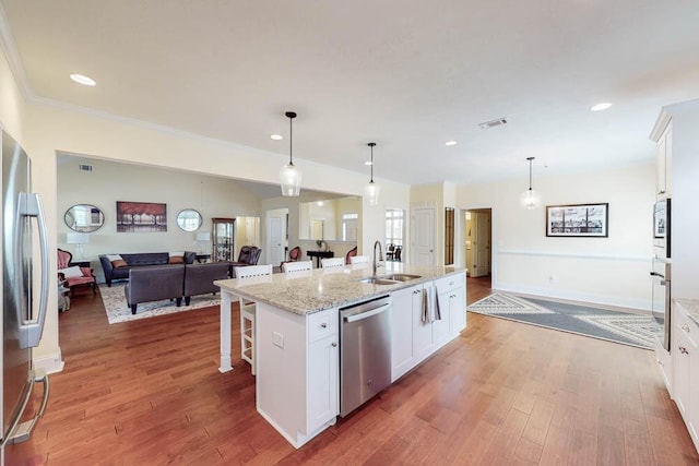 kitchen with a sink, a breakfast bar, wood finished floors, and stainless steel appliances