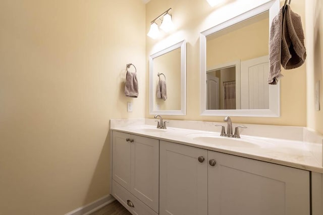 bathroom featuring double vanity, baseboards, and a sink