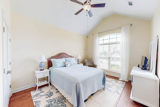 bedroom with baseboards, visible vents, light wood-style flooring, ceiling fan, and vaulted ceiling