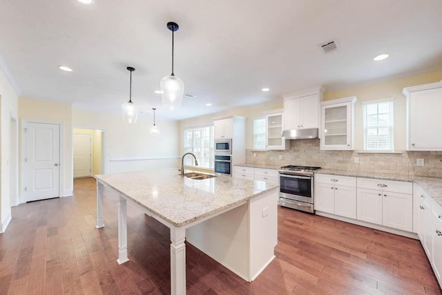 1190 Tralee Dr, Beech Island, SC 29842 - kitchen featuring appliances with stainless steel finishes, under cabinet range hood, a kitchen island with sink, tasteful backsplash, and wood finished floors