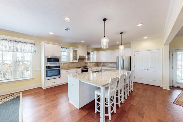 kitchen featuring a sink, dark wood-style flooring, backsplash, and stainless steel appliances